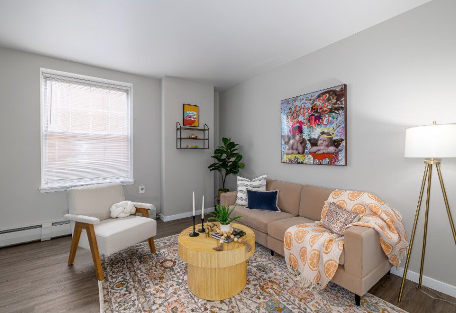 A living room with a couch, chair, and a painting on the wall.